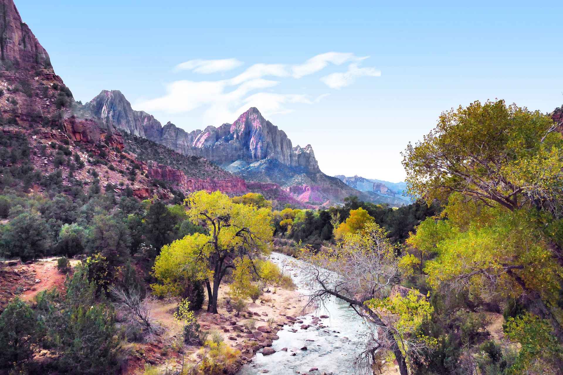 Autumn trees along the Virgin River below a sandstone peak in Zion National Park